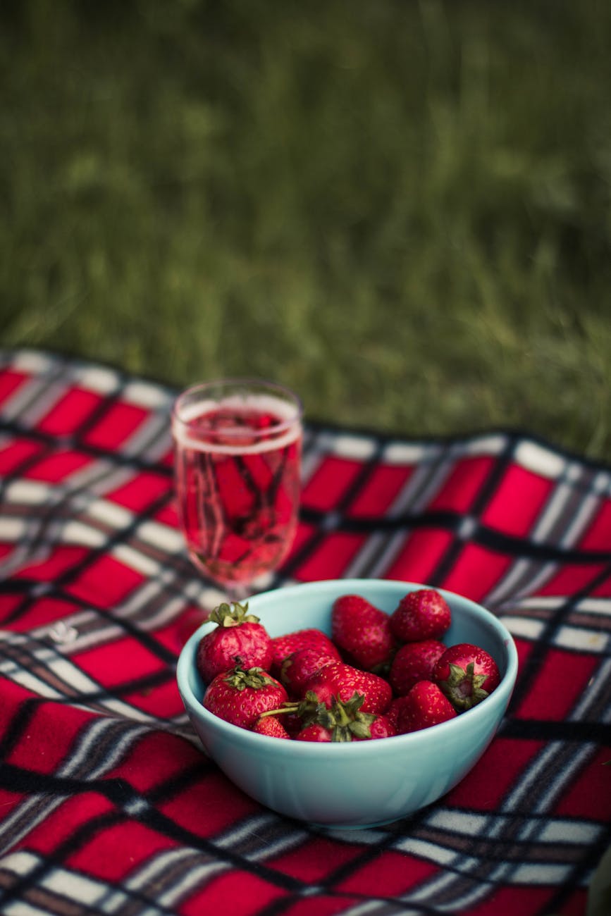 strawberry on white ceramic round bowl on pink white and brown plaid textile