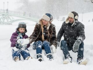 woman man and girl sitting on snow