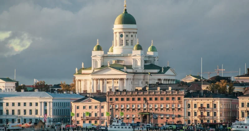 Auringonvalossa veden äärellä seisova katedraali, rauhallinen näky Helsingissä.