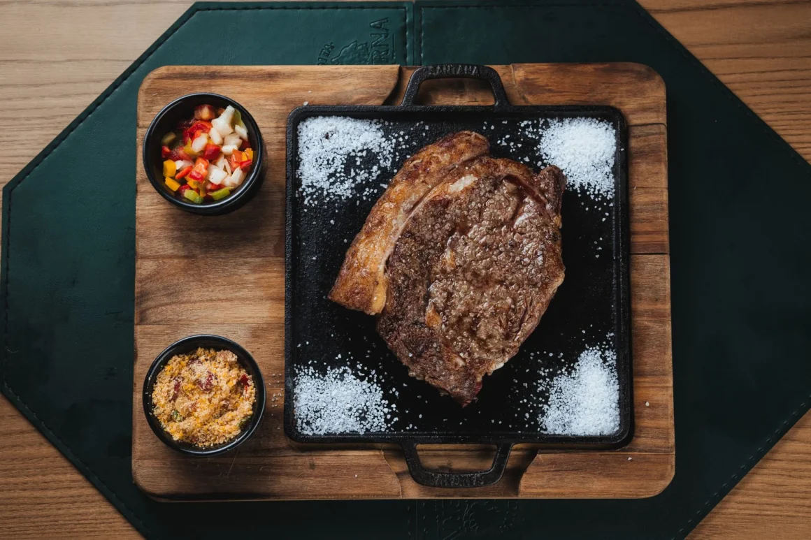 Grillattu ribeye-pihvi valurautapannulla lisukkeiden kanssa pihviravintolan tapaan