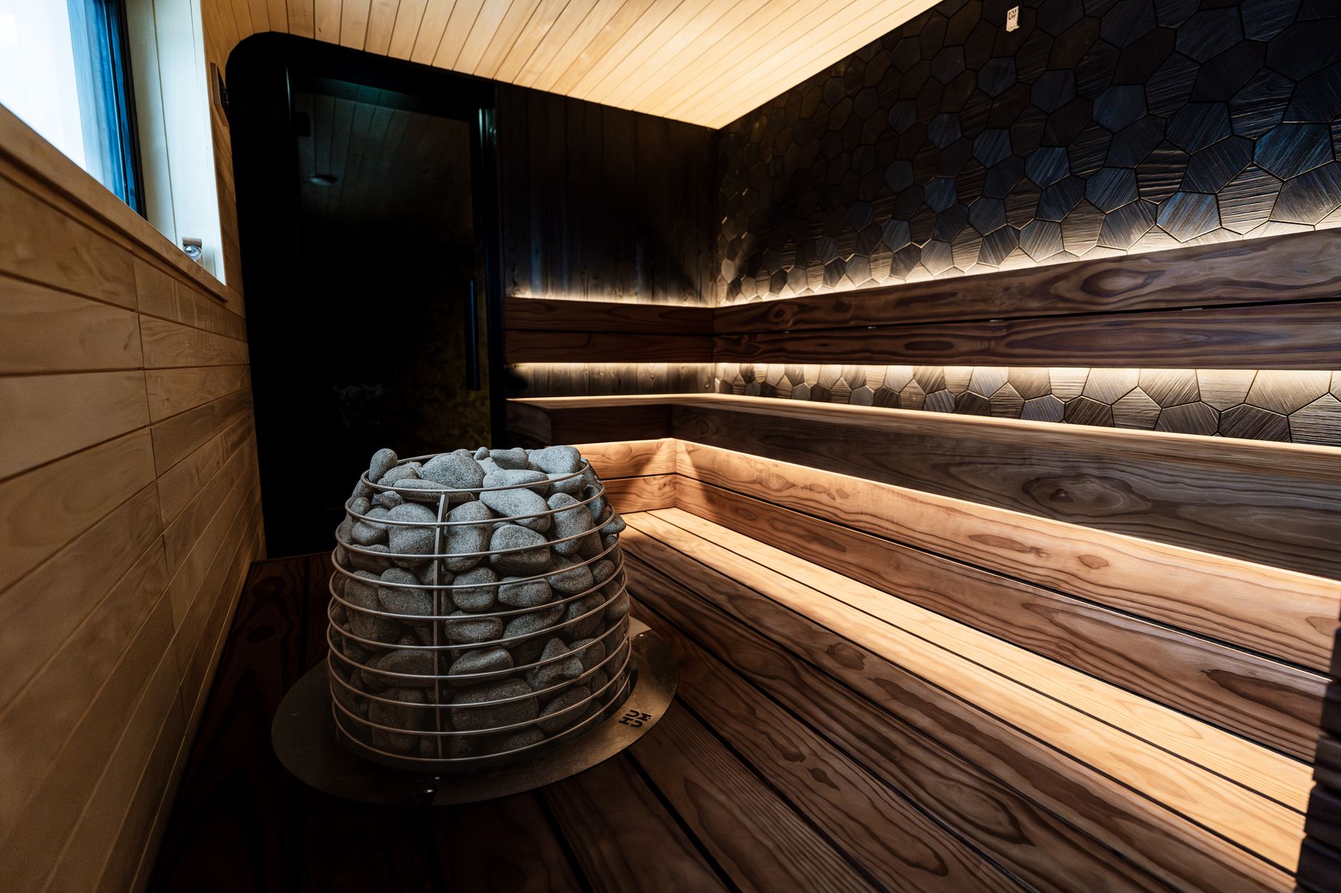 Moderni sauna, jossa puiset penkit ja valaistut kivet