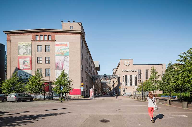 Kaapelitehtaan tiilinen päärakennus museoiden julisteineen ja KAAPELI-kyltti aurinkoisena kesäpäivänä Ruoholahdessa