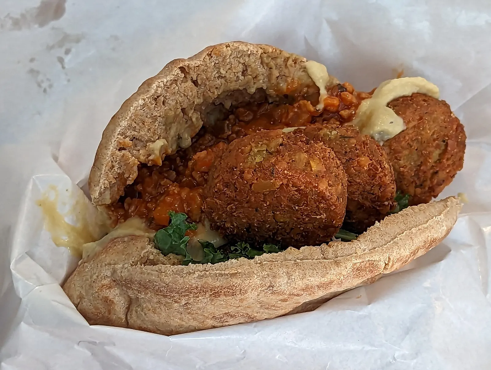 Falafel-pitaleipä hummuksella, lehtikaalilla ja punaisella kastikkeella