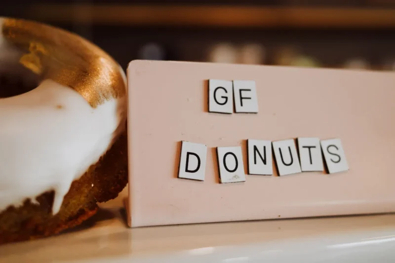 Gluteeniton donitsi valkoisella kuorrutteella ja GF DONUTS -kyltti kahvilan tiskillä