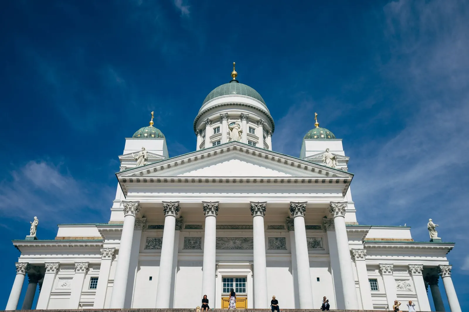 Helsingin tuomiokirkon valkoinen pylväspääty ja vihreät kupolit edestä kuvattuna