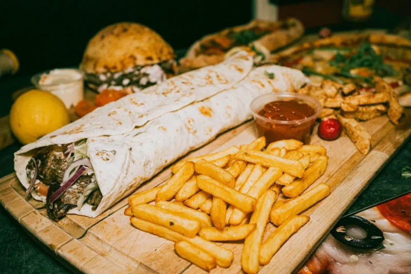 Kebab-käärö ja ranskalaiset perunat puisella tarjoilulaudalla