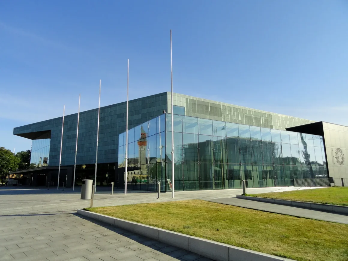 Musiikkitalon lasi- ja patinoitu julkisivu aurinkoisena päivänä Helsingissä