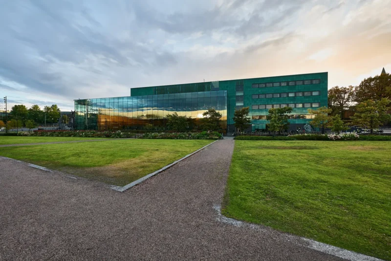 Musiikkitalon lasijulkisivu ja nurmikkoa Helsingin keskustassa iltavalossa